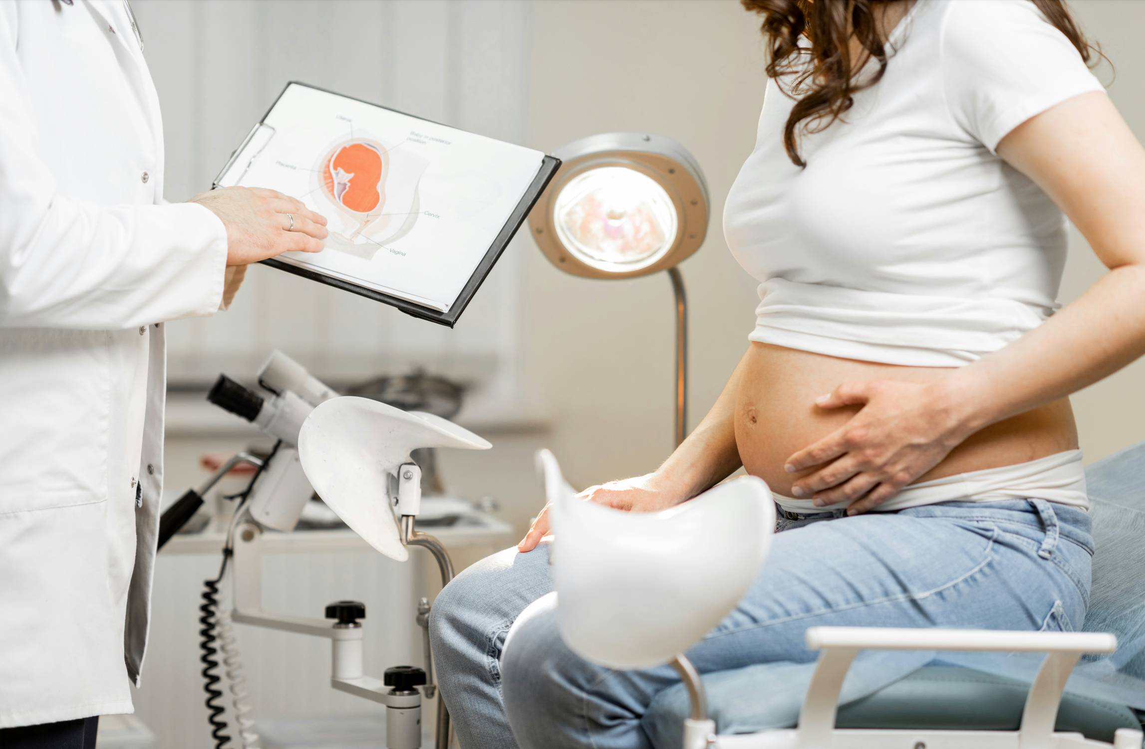 OB-GYN showing pregnant woman how to use Belly Bloom KT tape